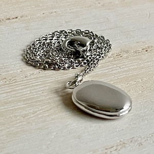 Tiny silver oval locket necklace personalized with up to two photos