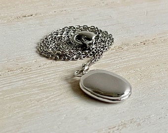 Tiny silver oval locket necklace personalized with up to two photos