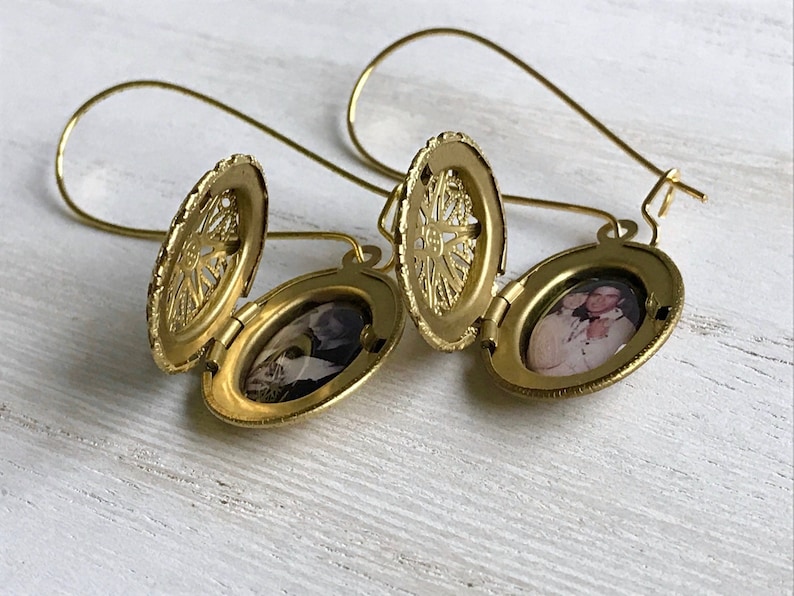 May include: Gold locket earrings with a filigree design and a photo of a couple inside. The earrings are open and the photo is visible.