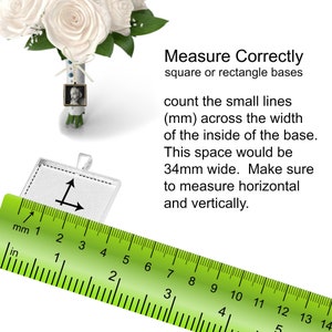 May include: A green ruler with black markings in inches and millimeters. The ruler is placed next to a silver picture frame with a white background. The image shows how to measure the inside of a picture frame for a custom photo insert.
