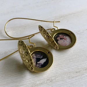May include: Gold locket earrings with a filigree design. Each locket features a photo of a couple.