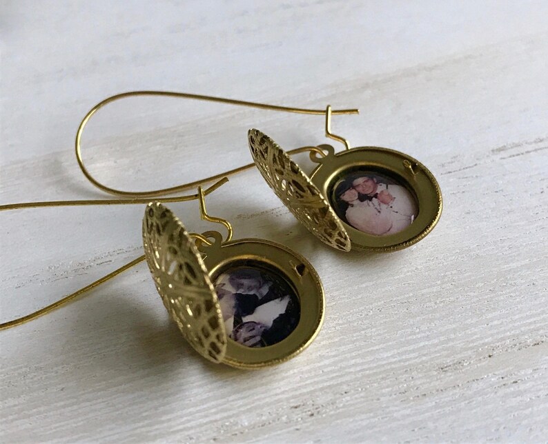 May include: Gold locket earrings with a filigree design. Each locket features a photo of a couple.