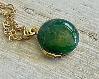 Puede incluir: Un collar de oro con un colgante redondo de color verde y amarillo marmoleado.