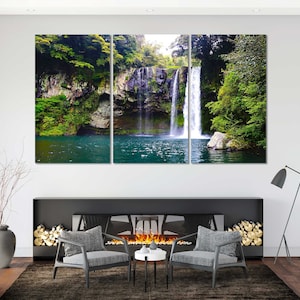 May include: A three-panel canvas print featuring a waterfall cascading down a rocky cliff face, surrounded by lush green foliage. The water is clear and blue, and the surrounding vegetation is vibrant and verdant.