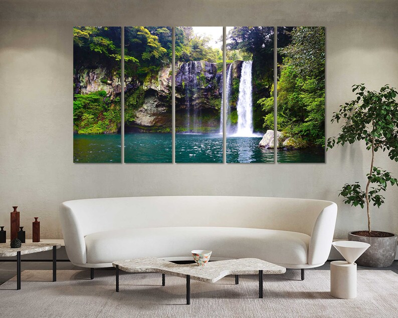 May include: A panoramic photograph of a waterfall cascading down a rocky cliff face, surrounded by lush green foliage. The water is clear and blue, and the surrounding vegetation is vibrant and healthy.
