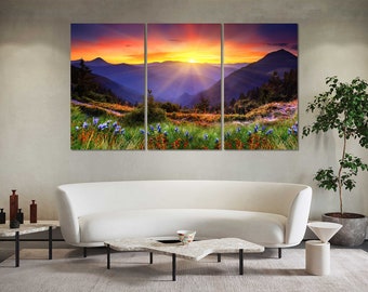May include: A three-panel canvas print depicting a scenic mountain landscape with a vibrant sunset. The image features a mountain range with lush green vegetation and a bright orange and yellow sunset in the background. The canvas print is perfect for adding a touch of nature to any room.
