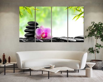 May include: A multi-panel canvas print featuring a pink orchid flower and stacked black stones on a green and white background. The print is displayed on a white couch in a living room setting.