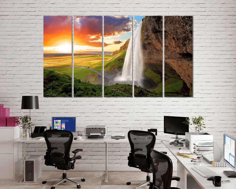 May include: A multi-panel canvas print featuring a scenic landscape with a waterfall cascading down a rocky cliff. The sky is a vibrant orange and pink, with clouds in the distance. The waterfall is surrounded by lush green vegetation.
