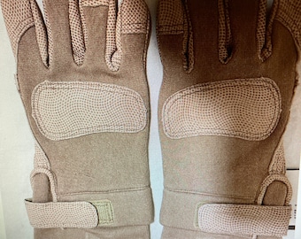 May include: A pair of tan tactical gloves with a velcro strap on the wrist. The gloves have a textured palm and fingertip area.