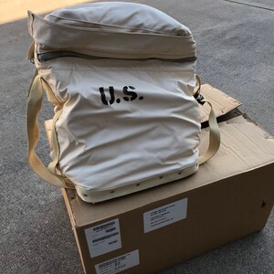 May include: A white canvas bag with a zipper closure and a black "U.S." logo. The bag is sitting on top of a brown cardboard box with a shipping label.
