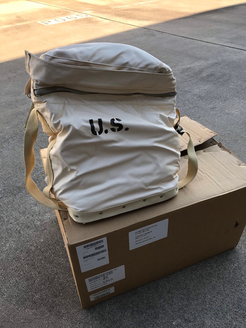 May include: A white canvas bag with a zipper closure and a black "U.S." logo. The bag is sitting on top of a brown cardboard box with a shipping label.
