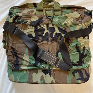 May include: A camouflage green duffel bag with a black shoulder strap and a zip closure.