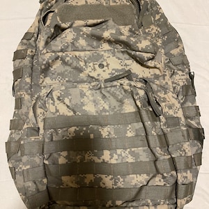 May include: A camouflage-patterned backpack with multiple straps and pockets.