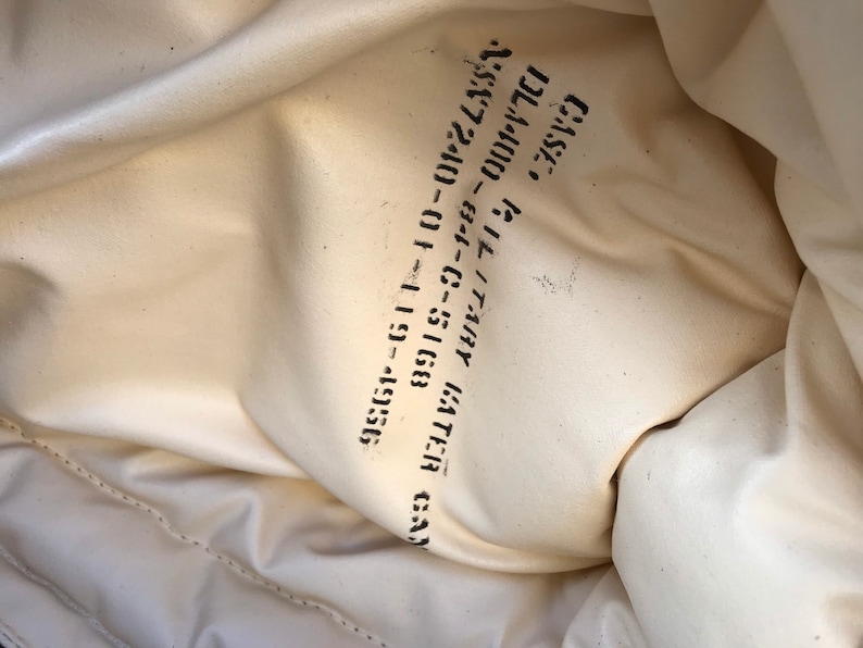 May include: Close-up of a white fabric bag with black text that reads "GATHER GA 95357-5168 01-11-5168 C-5168Y 82-81-C-7344Y GATHER GA 2/SK 72400 - 01 11 5168 DL44000"