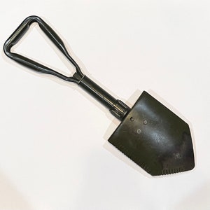 May include: A black folding shovel with a green handle. The shovel has a pointed blade and a folding handle.
