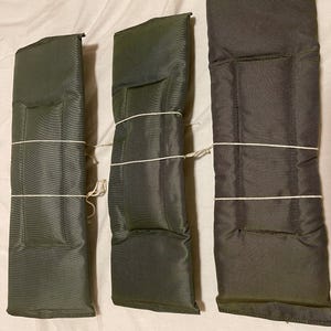 Puede incluir: Tres correas acolchadas verdes y marrones con una cuerda blanca atada alrededor.
