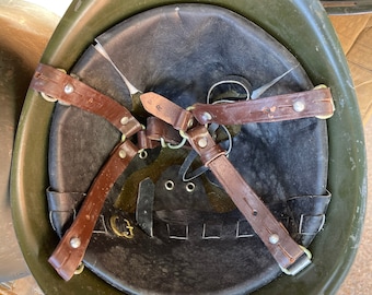 May include: A green military helmet with a brown leather strap system. The helmet has a black liner and is in used condition.