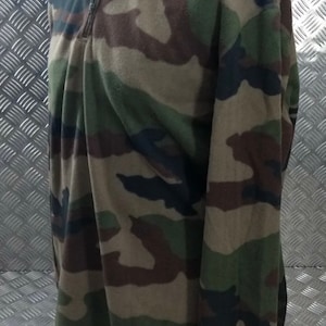 以下が含まれることがあります： ジッパー付きの襟が付いた迷彩柄のフリースプルオーバー。フリースは濃い緑色、茶色、黒の迷彩柄です。