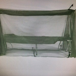 May include: A green mosquito net with a rectangular frame and metal hooks. The net is suspended over a bed or cot.