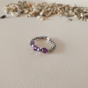 May include: A silver ring with purple amethyst beads and silver beads.