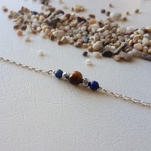 以下が含まれることがあります： 茶色のタイガーアイビーズと2つの青いラピスラズリビーズが付いたシルバーチェーンブレスレット