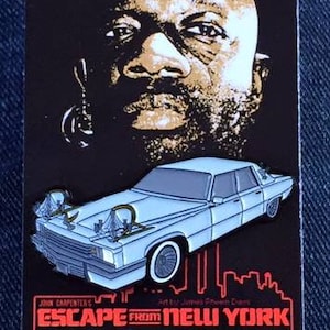 May include: A rectangular pin featuring a portrait of a man above a light blue car. The pin includes the text "ESCAPE FROM NEW YORK THE DUKE" in red, with the Hellraiser Designs logo.