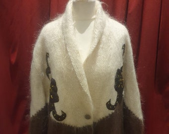 May include: A white and brown fuzzy cardigan with a button closure and black and gold embroidered seahorse designs.
