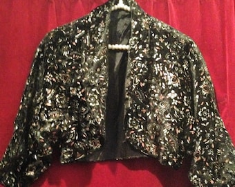 May include: A black velvet cropped jacket with a floral pattern in silver and pink.