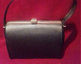 May include: A black leather handbag with a silver clasp and a short handle.
