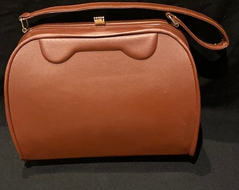 May include: A brown leather handbag with a gold clasp and a single handle.