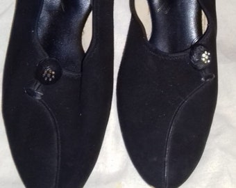 May include: A pair of black suede shoes with a pointed toe and a small decorative button on the front. The shoes have a low heel.
