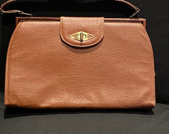 May include: A brown leather handbag with a gold clasp and a single strap.