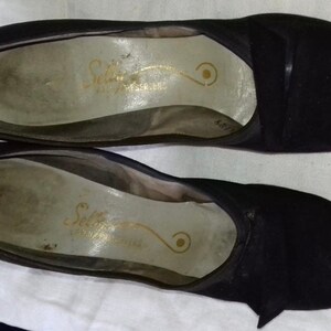May include: A pair of black peep-toe heels with a gold inscription that reads "Selby Fifth Avenue" on the insole.