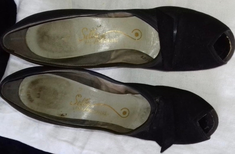 May include: A pair of black peep-toe heels with a gold inscription that reads "Selby Fifth Avenue" on the insole.