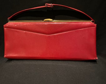 May include: A red leather clutch purse with a gold clasp and a short handle.
