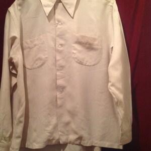 May include: A white long-sleeved button-down shirt with two chest pockets.