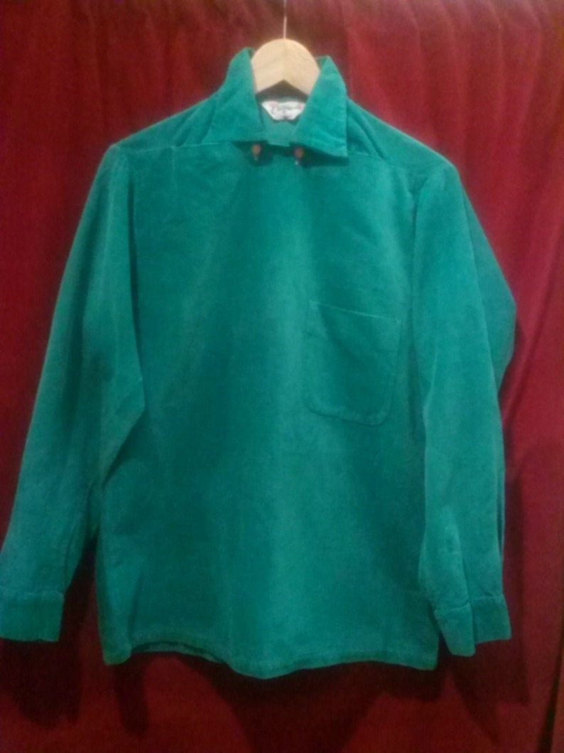 May include: A long-sleeved, green corduroy shirt with a button-down collar and a single pocket on the left side.