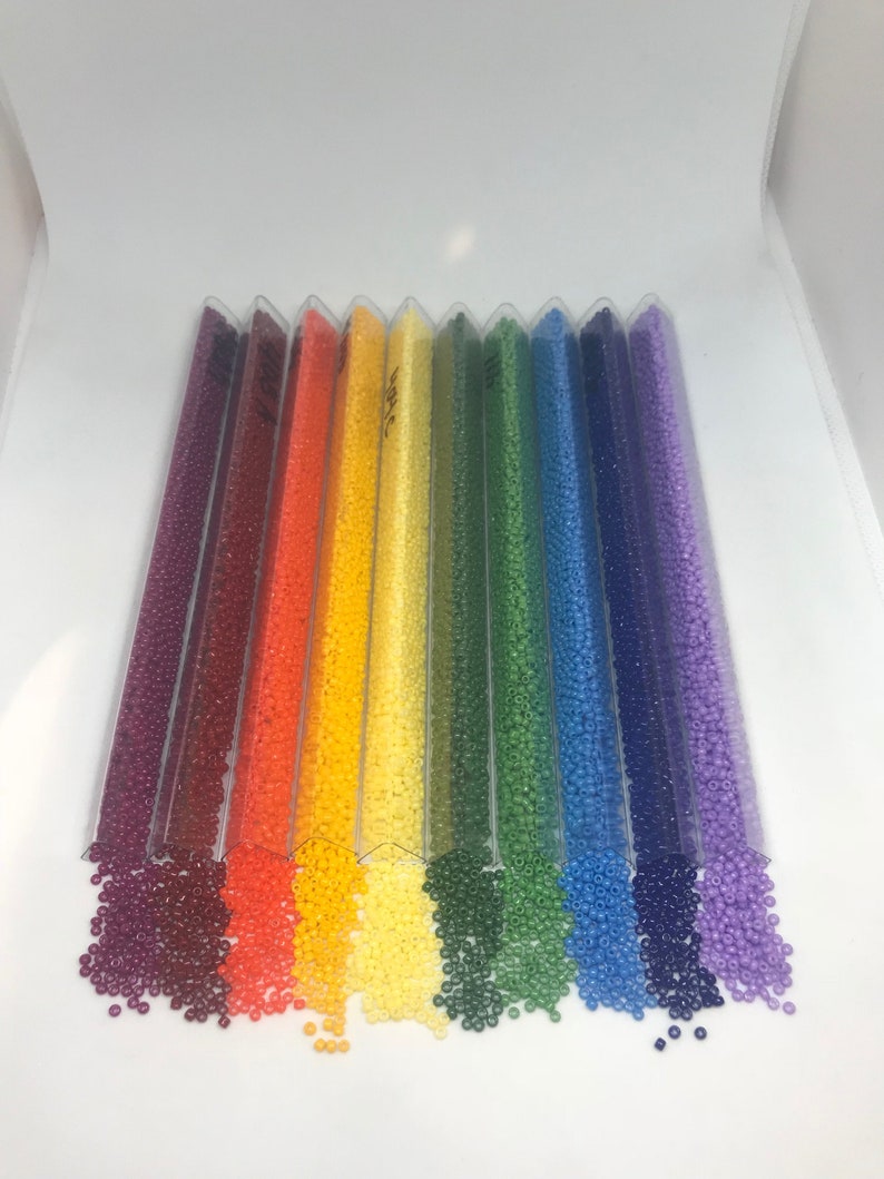 May include: Assortment of colorful seed beads in clear plastic tubes. The beads are arranged in a rainbow pattern, with red, orange, yellow, green, blue, and purple beads.