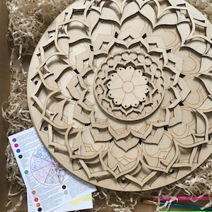 May include: A wooden mandala art kit with multiple layers of intricate designs. The kit includes a wooden base, paintbrushes, and a color chart.