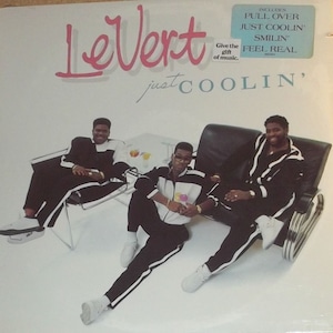 May include: A record album cover featuring a group of three men in black and white outfits, sitting on chairs and couches. The album title is "Le Vert" and the album name is "Just Coolin'" with the words "Give the gift of music." printed below the title.
