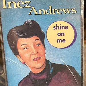 May include: A sealed cassette tape featuring Inez Andrews. The album cover has a portrait of Andrews with the text "shine on me" in a yellow circle. The background is a gradient of blue.