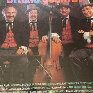 May include: Album cover for Zinn's Ragtime String Quartet. The image features four men in formal attire, posing with a cello. The album title is in colorful, retro lettering. The cover lists song titles by Scott Joplin, Eubie Blake, and others.