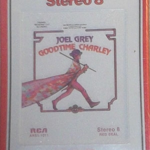 May include: A vintage 8-track cassette tape case with a silver background and red border. The case features a colorful illustration of Joel Grey as "Goodtime Charley" from the musical "Goodtime Charley". The text "Stereo 8" is printed in black at the top of the case. The text "RCA" is printed in black at the bottom of the case.