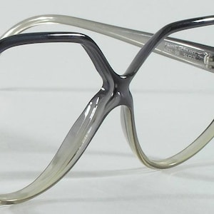 May include: Gray plastic framed eyeglasses with a geometric shape. The frames have a slight gradient from dark gray to light gray.