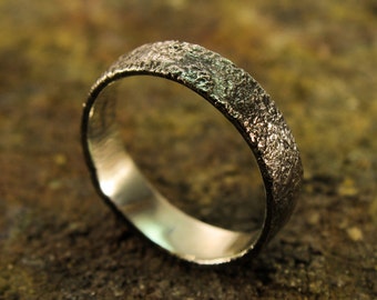 Puede incluir: Una banda de boda de plata con un acabado texturizado y martillado.