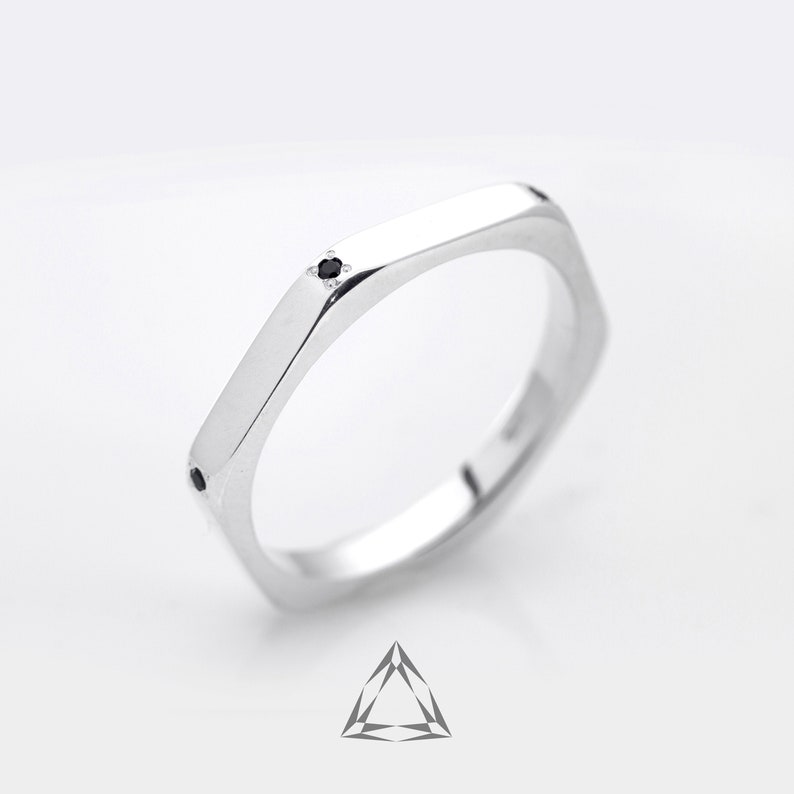 May include: A silver hexagonal ring with a small black gemstone set in the center.
