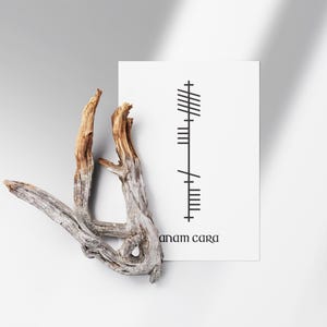 Anam Cara (Soulmate) text below Ogham script that translates to Anam Cara, Irish for Soulmate. Black Ogham lettering and text on a clean white background in a modern minimalist style.