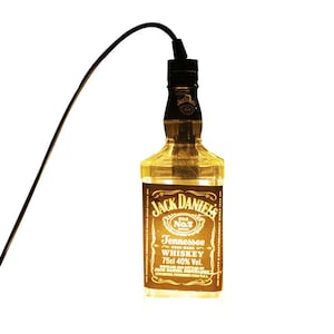 Könnte beinhalten: Eine klare Glasflasche Jack Daniel's Old No. 7 Tennessee Whiskey mit schwarzem Verschluss und schwarzem Kabel. Die Flasche hat ein braunes Etikett mit weißem Text. Die Flasche enthält 75cl mit 40% Vol. Whiskey.