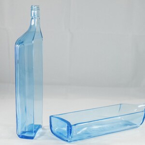 Pu&ograve; includere: Due bottiglie di vetro blu chiaro. Una &egrave; in posizione verticale e l'altra &egrave; sdraiata. Le bottiglie hanno una forma rettangolare con angoli arrotondati e un collo stretto. Le bottiglie sono in vetro trasparente.