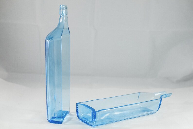 Pu&ograve; includere: Due bottiglie di vetro blu chiaro. Una &egrave; in posizione verticale e l'altra &egrave; sdraiata. Le bottiglie hanno una forma rettangolare con angoli arrotondati e un collo stretto. Le bottiglie sono in vetro trasparente.